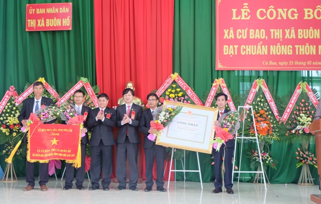 Phó Bí thư Thường trực Tỉnh uỷ Phạm Minh Tấn (người thứ 3 từ trái sang) trao Bằng công nhận và Cờ thi đua của UBND tỉnh tặng chính quyền và nhân dân xã Cư Bao.