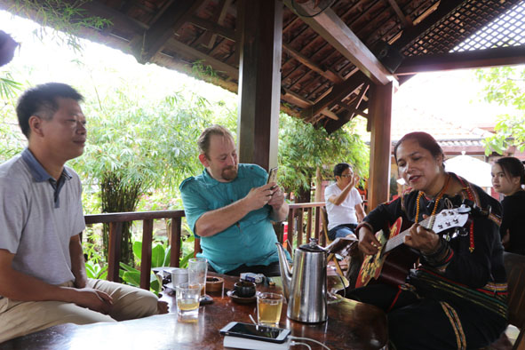 Du khách nước ngoài thích thú thưởng thức cà phê và giao lưu văn nghệ với chị H'Len - chủ quán cà phê Arul.