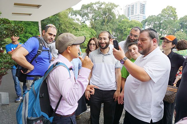 Hướng dẫn viên du lịch (áo hồng) đang hướng dẫn du khách nước ngoài tham quan Dinh Thống Nhất, TPHCM – Ảnh: Đào Loan